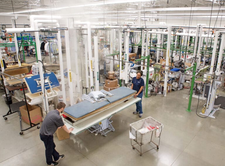 Steam shown rising from a pressing station, which is just one of the many pieces of equipment that is connected by piping to the steam generated by Fulton's VMP-100.